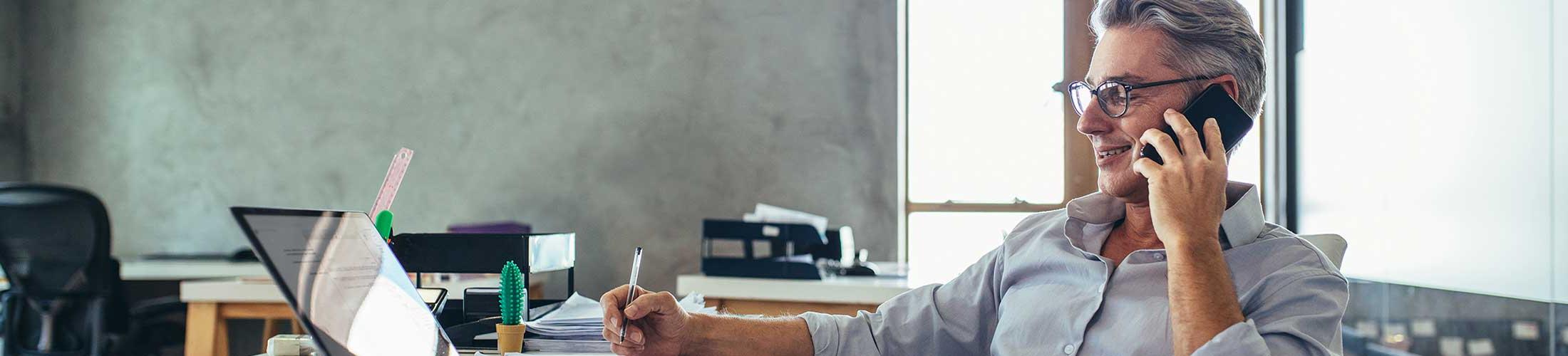 Man talking on phone working at desk.