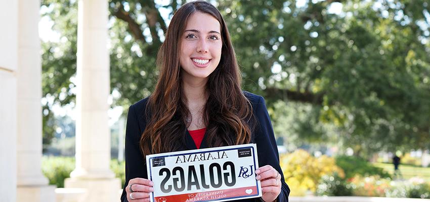 Student holding up Go Jags USA license plate.